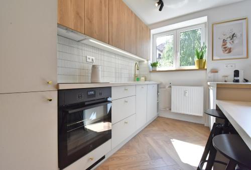 una cocina con armarios blancos y horno negro en Bulvár 84 Apartment, en Žilina