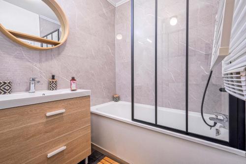 uma casa de banho com uma banheira, um lavatório e um espelho. em Apart' Minnie - Disneyland Paris - 3 Bedrooms - Parking privé em Magny-le-Hongre
