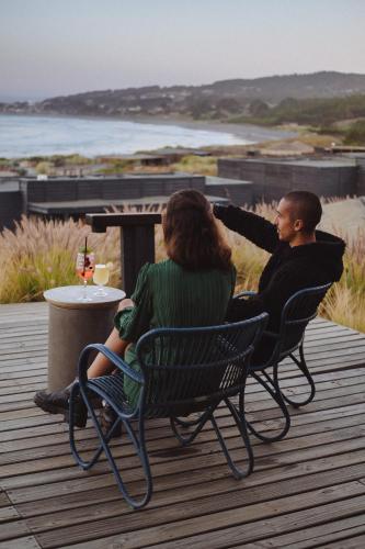 a man and a woman sitting in chairs on a deck at Hotel Alaia in Pichilemu