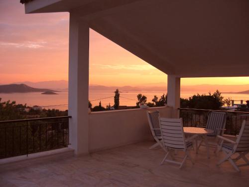 a balcony with chairs and a view of a sunset at Villa Bellevue in Nea Stira