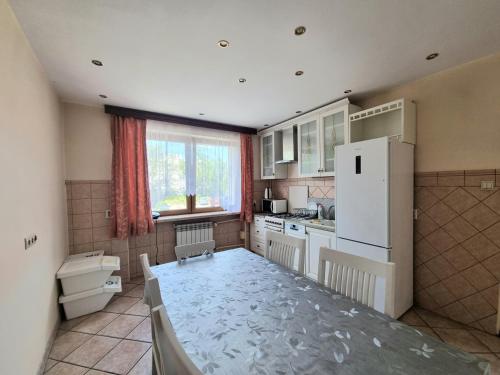 a kitchen with a table and a white refrigerator at Hostel Rumiankowy Airport Hostel in Wrocław