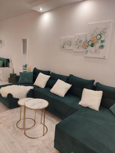 a living room with a green couch and a table at Emerald Apartman in Szeged