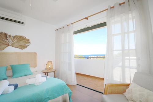 a bedroom with a bed and a large window at Villa Las Marinas - 2 Encantadora Villa con piscina a 5 min de la playa in Arenal d'en Castell
