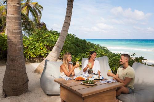 a group of people sitting at a table on the beach at Lula Seaside Boutique Hotel in Tulum
