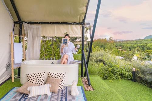a woman taking a picture in a bath tub in a tent at SOL Glamping at Khao yai in Ban Nong Makha