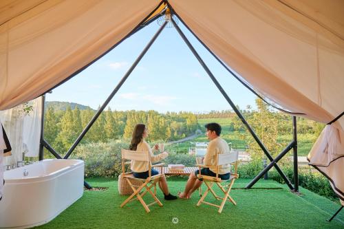 a couple sitting in chairs in a tent with a bathtub at SOL Glamping at Khao yai in Ban Nong Makha