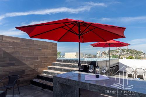 a table with two red umbrellas on a patio at NewModern~5 Area~Walk 2 Beach~Pool~View~King Bed in Mazatlán