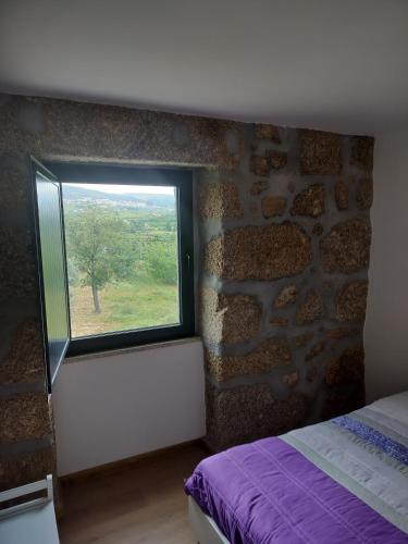 a bedroom with a window in a stone wall at Arpuro in Gouveia