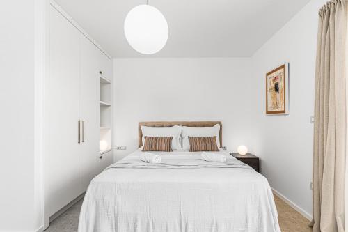 a white bedroom with a large bed with white sheets at Belsize Villas in Budva