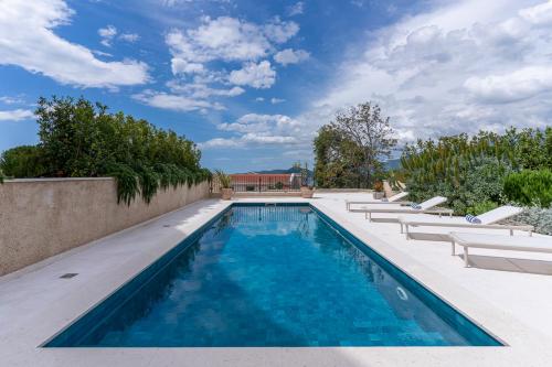 a swimming pool with lounge chairs next to a wall at Belsize Villas in Budva