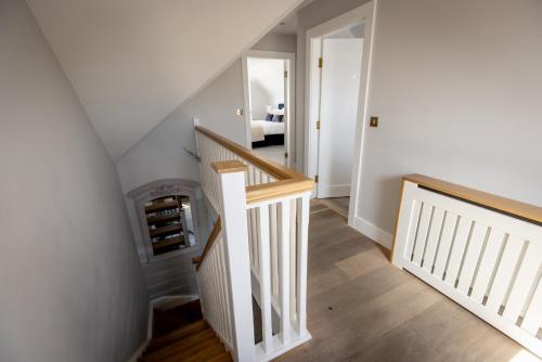 a hallway with a staircase with white walls and wooden floors at Coastal View House in Doolin