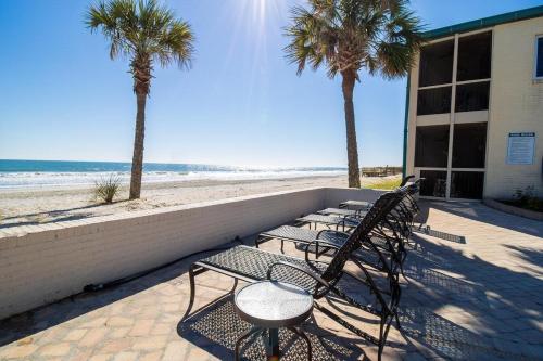 a row of chairs and palm trees next to the beach at Steps From Beach Sleeps 4 Beautiful Views in Pawleys Island