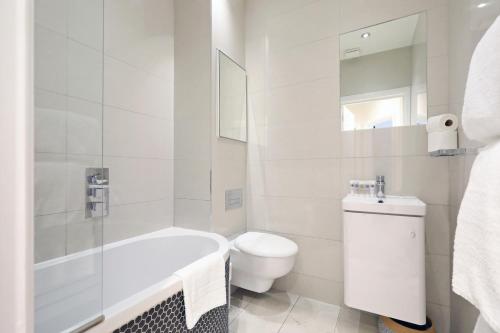 a white bathroom with a tub and a toilet at Covent Garden Superior Two Bedroom Aparment on Strand in London