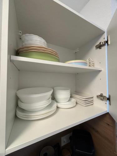 a white cabinet filled with plates and bowls at Nisay Home - City House - Central Location - 5 Rooms in Ludwigsburg