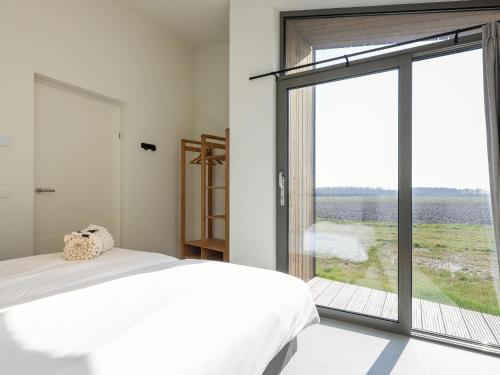 Un dormitorio con una cama y una ventana grande. en Cottage in Wissenkerke near Nature Reserve, en Wissenkerke
