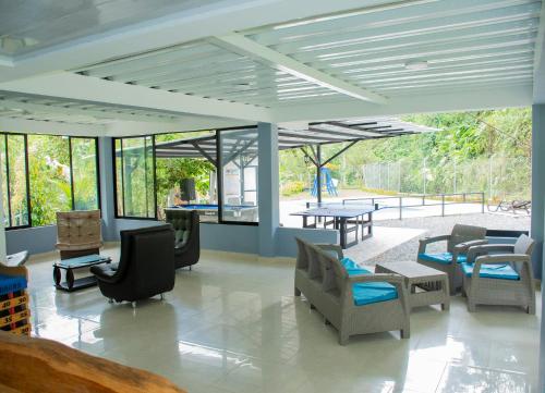 a living room with chairs and tables and windows at Finca hotel el porvenir in Quimbaya