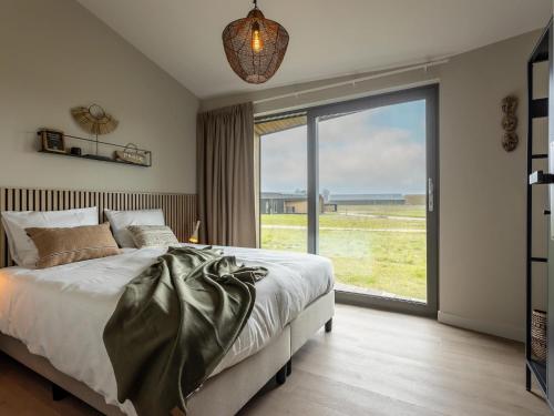 a bedroom with a large bed and a large window at Nature Escape w Sauna in Wissenkerke