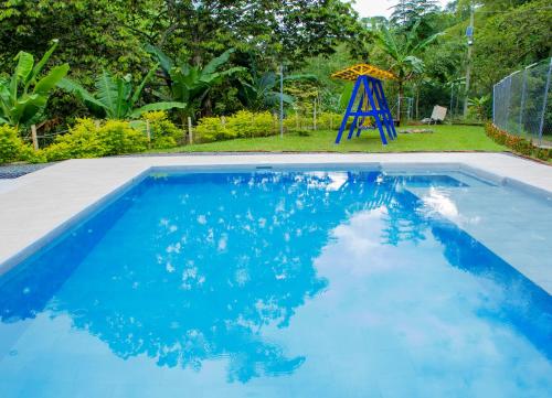 a blue swimming pool with a slide and a playground at Finca hotel el porvenir in Quimbaya