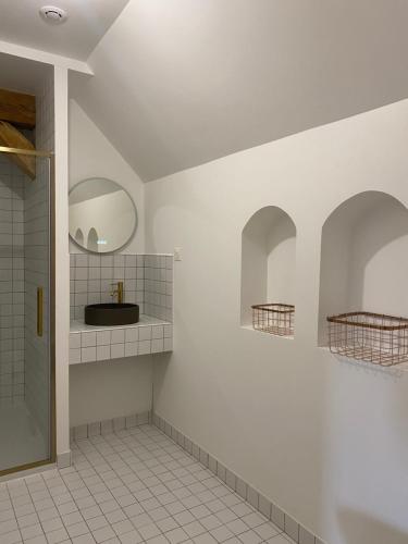La salle de bains est pourvue de murs blancs, d'un lavabo et d'un miroir. dans l'établissement L'appartement d'Armentières, à Saint-Benoist-sur-Vanne