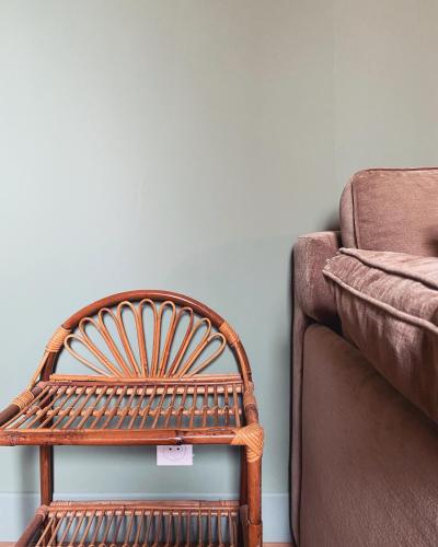 une chaise en bois à côté d'un canapé avec un panneau dessus dans l'établissement L'appartement d'Armentières, à Saint-Benoist-sur-Vanne