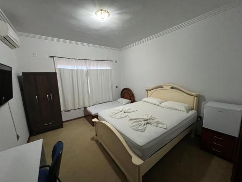 een slaapkamer met een bed, een dressoir en een raam bij Suíte no centro com 2 camas e hidromassagem in Sinop