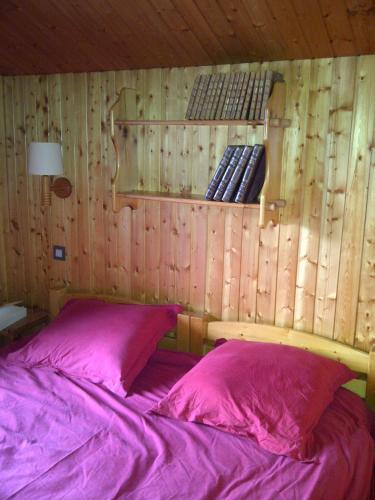 a bedroom with a bed with pink sheets and wooden walls at L'arpont in Champagny-en-Vanoise