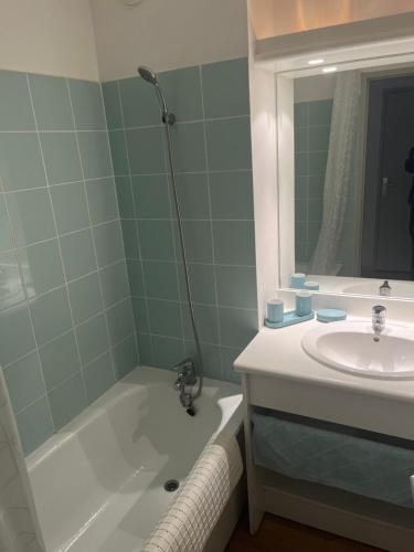 ein Badezimmer mit einem Waschbecken, einer Badewanne und einem Spiegel in der Unterkunft Appartement T3 équipé in Carantec