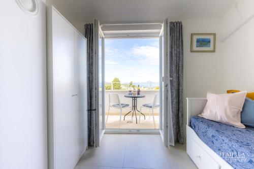 a bedroom with a bed and a balcony with a table at Citadela Veli Lošinj in Veli Lošinj