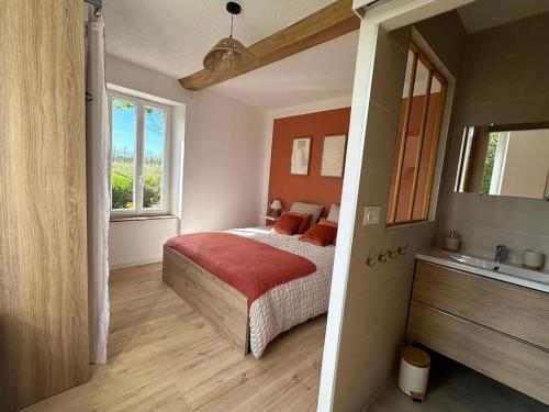 Un dormitorio con una cama con una manta roja. en Le Petit Portais, en Port-en-Bessin-Huppain