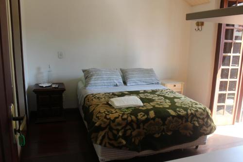 a bedroom with a bed with a blanket and pillows at Mansão Residence & Club in Vassouras