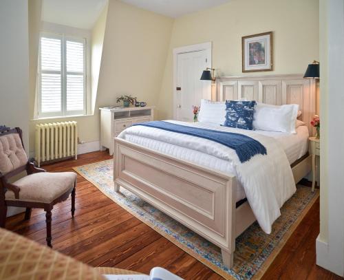 a bedroom with a large bed and a chair at Old Manse Inn in Brewster