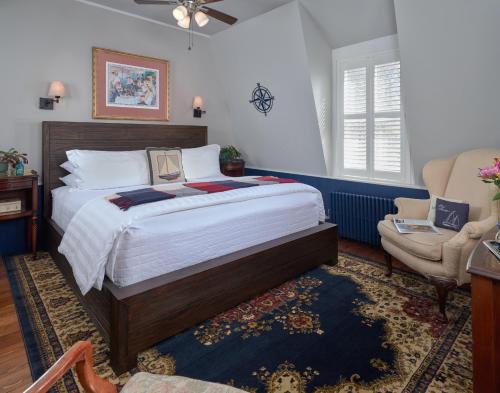 a bedroom with a large bed and a chair at Old Manse Inn in Brewster