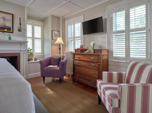 a bedroom with a tv and a chair and a dresser at Old Manse Inn in Brewster
