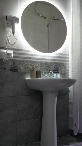 ein Badezimmer mit einem weißen Waschbecken und einem Spiegel in der Unterkunft Eleven Guest House in Kutaissi
