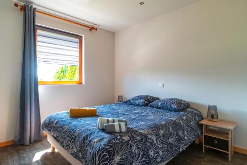 Un dormitorio con una cama con edredón azul y una ventana. en Cocon vert proche mer, en Plouhinec