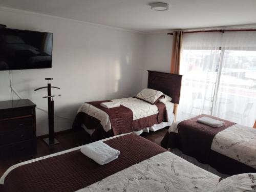Habitación con 3 camas y una cruz en la pared. en HOTEL QUINTA ESTACIÓN, en Caldera
