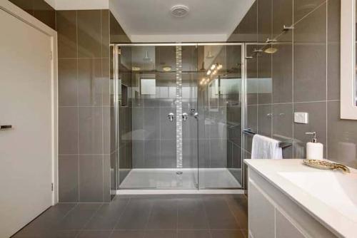 Un baño con ducha con puerta de cristal. en Dromana Grove SPA & POOL sleeps 15, en Dromana