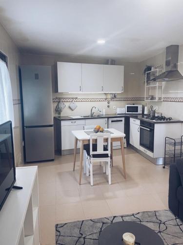 a kitchen with a table and a kitchen with white appliances at Casinha do Lagar in Nadadouro