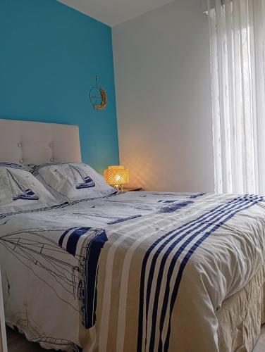 une chambre avec un grand lit avec un mur bleu dans l'établissement Appart proche plage pied dans l'eau avec terrasse jardin vue sur le bassin depuis la terrasse, à Arcachon