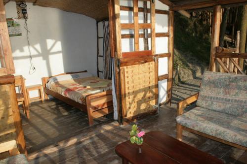 KabaleにあるAmasiko Homestay Lake Bunyonyiのベッド、ソファ、テーブルが備わる客室です。