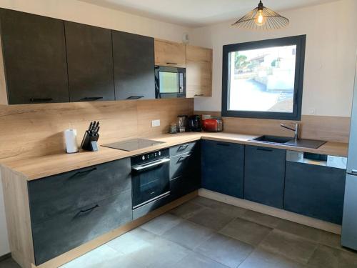 a kitchen with black appliances and a window at Appartement récent, tout confort , vue mer, plage à 5min in Propriano