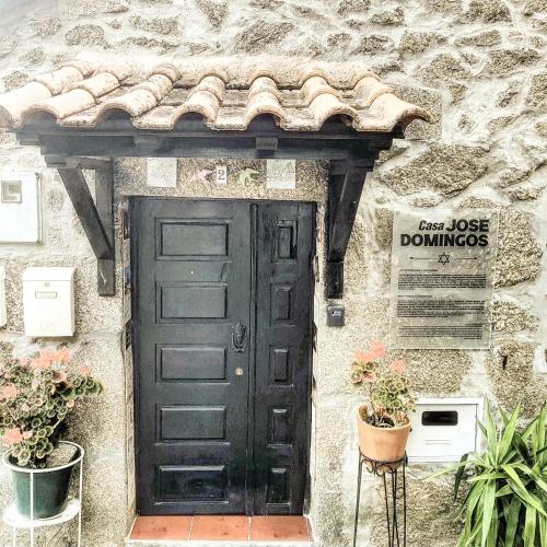 a black door in a stone building with plants at José Domingos in Belmonte