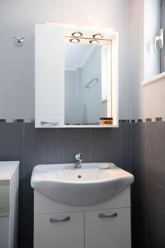 a white bathroom with a sink and a mirror at Laconian Blue Residence in Gythio
