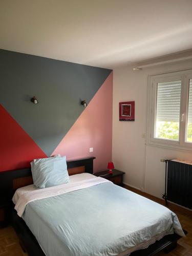 Un dormitorio con una cama con una pared roja y gris. en Champs Bernard, en Villefranche-de-Rouergue