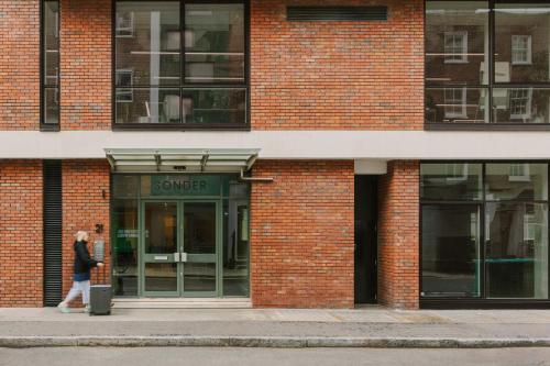 una mujer caminando delante de un edificio en Sonder The Bard, en Londres