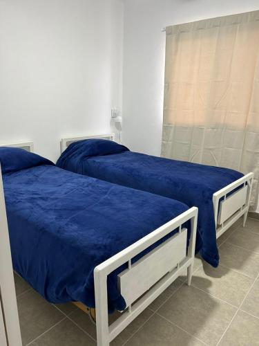 two beds with blue sheets in a room at La Celestina in Ramallo