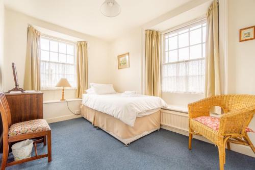 ein Schlafzimmer mit einem Bett und einem Stuhl und Fenstern in der Unterkunft Hillside Cottage in Ambleside