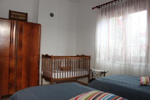 a bedroom with two beds and a crib and a window at Boulevard Garden House - Free and save parking in the locked yard in Ćuprija