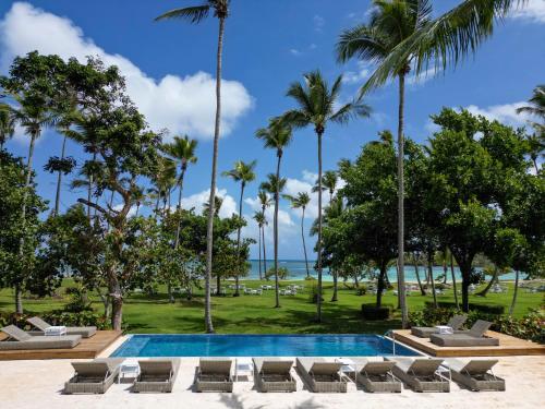 a resort pool with lounge chairs and palm trees at Wyndham Alltra Samana All Inclusive Resort in Las Galeras