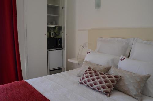 a bedroom with a bed with white sheets and pillows at Entre Vinhas & Mar in Óbidos